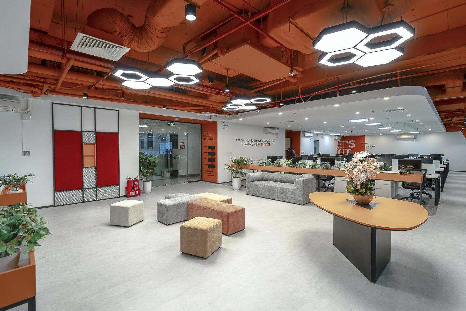 Không gian làm việc mở của văn phòng Wisewires với trần cam nổi bật, đèn hình học và khu chờ hiện đại