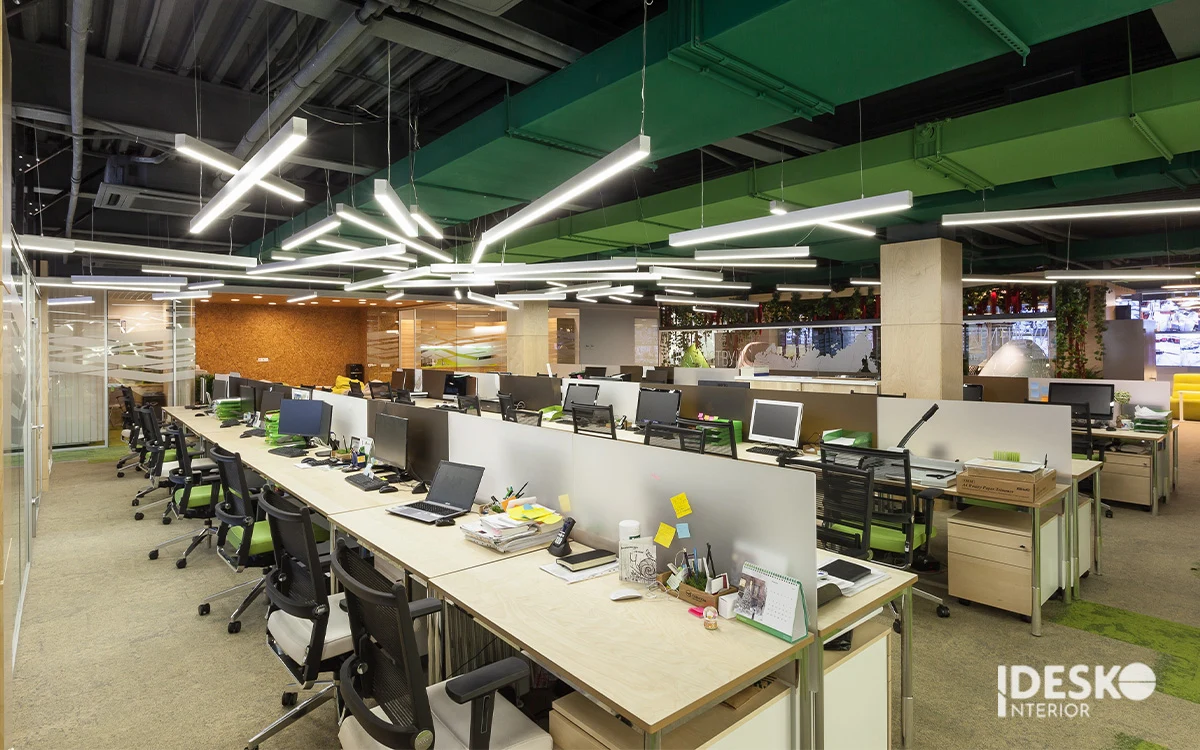 Khu làm việc mở với dãy bàn dài, trần kỹ thuật lộ và hệ đèn treo tạo điểm nhấn hiện đại