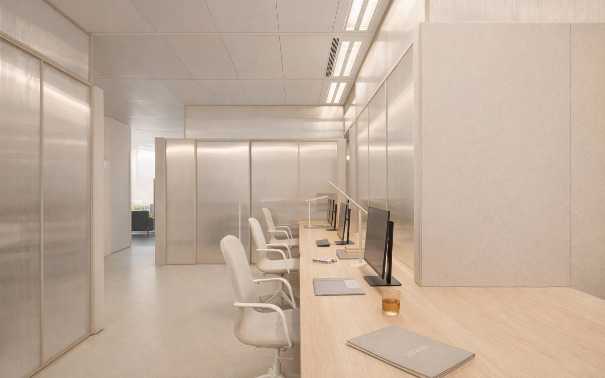 Góc làm việc trong văn phòng startup với bàn liền dài, tông be nhẹ và bố cục tối giản, thư thái