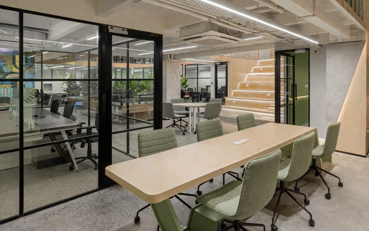 Khu họp mở trong văn phòng startup với vách kính, bàn dài và bố cục linh hoạt cho trao đổi nhóm