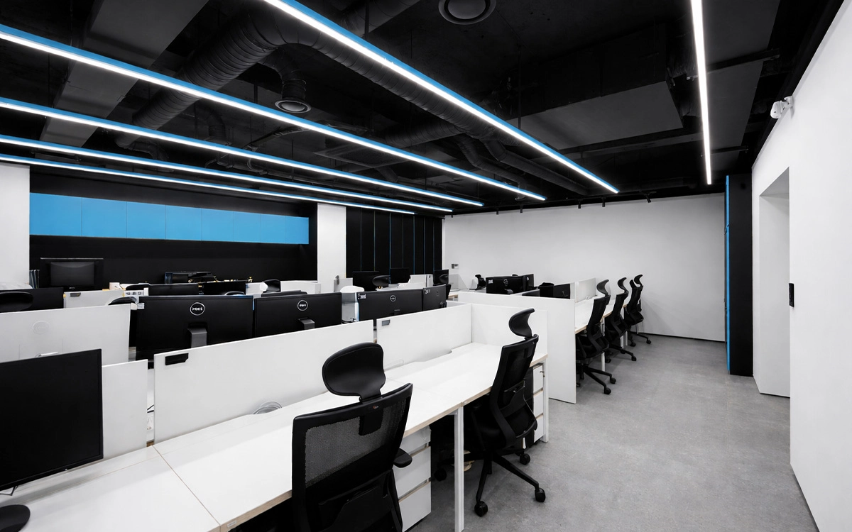 Thiết kế văn phòng startup với khu làm việc tập trung, tông đen trắng mạnh mẽ và hệ đèn trần tạo điểm nhấn hiện đại