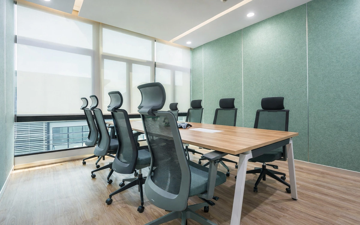 Phòng họp văn phòng startup với bàn gỗ đơn giản, ghế lưới đồng bộ và tông xanh tạo cảm giác tập trung