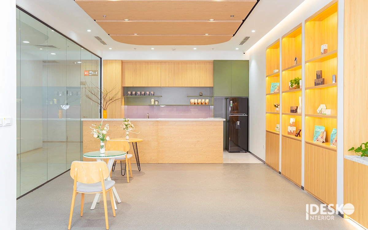 Thiết kế khu pantry với gam màu gỗ sáng, hệ tủ trưng bày tinh gọn và không gian thư giãn nhẹ nhàng, phù hợp xu hướng nội thất văn phòng hiện đại